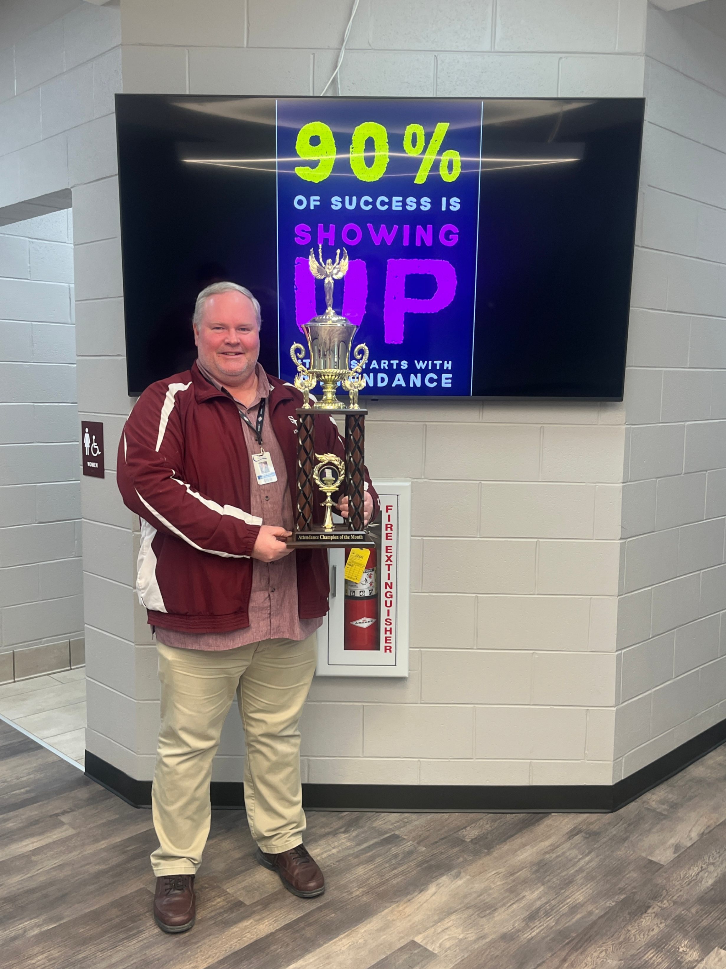 Principal Ben East holding the attendance trophy.